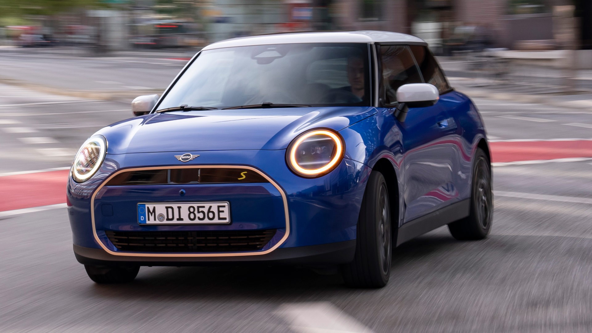 Blár rafknúinn MINI Cooper á ferð eftir borgargötu